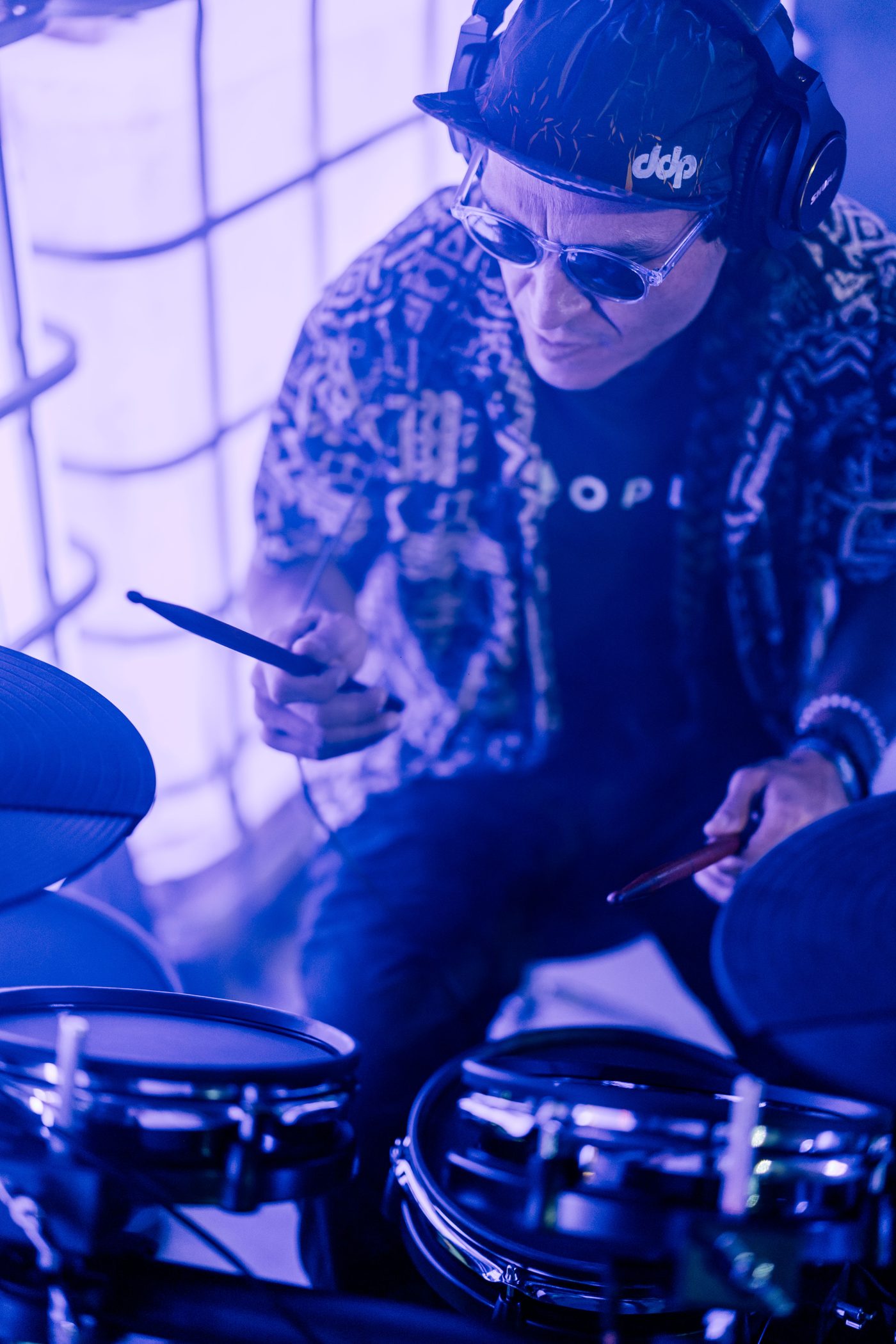 Drummer in cap and sunglasses deep in the groove