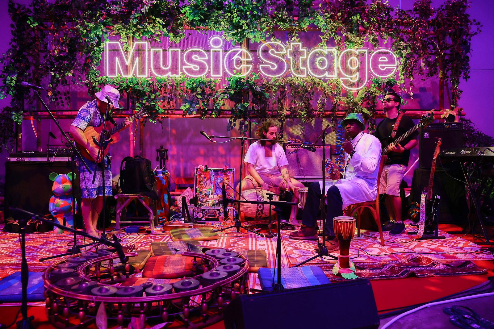 The Music Stage at Devcon SEA — neon sign, jungle leaves, musicians and instruments in a circle