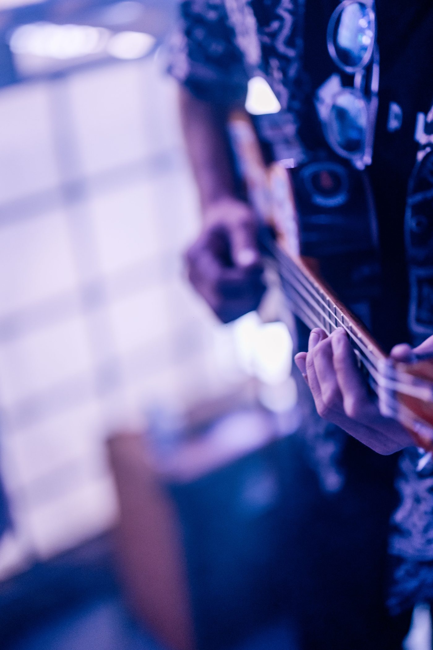 Close-up of hands on the ukulele fretboard, stage lights bokeh
